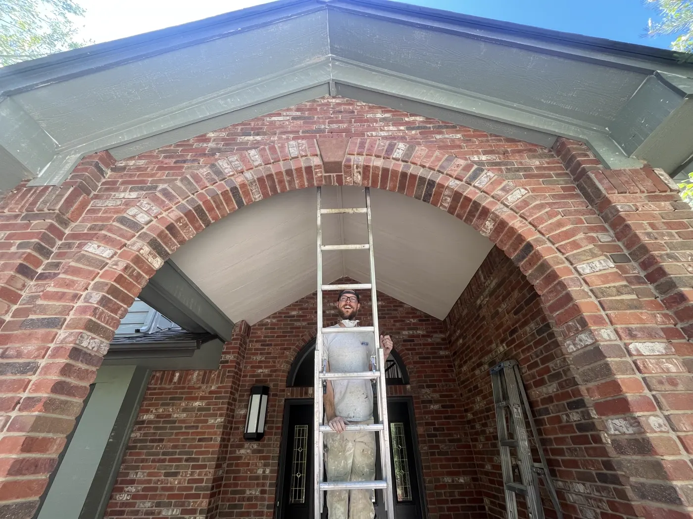 Painter on a ladder inside a brick archway entrance